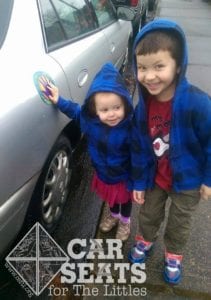 Two children standing next to car in parking lot waiting with their hand on the spot on the car designated by a sticker